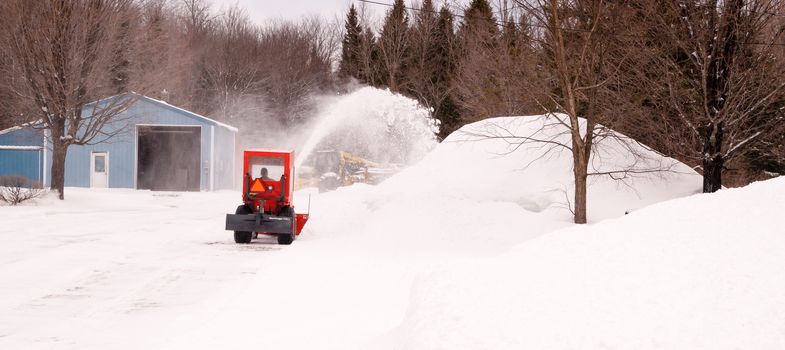 Small snowblowing tractor takes on the driveway after a long night of snowfall