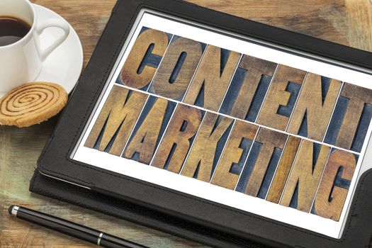 content marketing  - text in grunge letterpress wood type printing blocks on a digital tablet with a cup of coffee