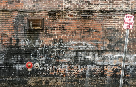 Horizontal shot of an old brick wall covered in graffiti and paints.