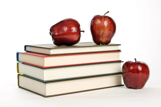 Horizontal shot of stack of books and red apples on white background