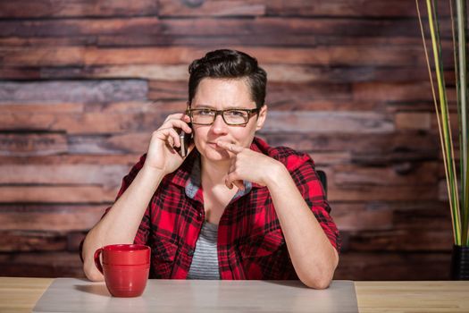 Thinking office worker with eyeglasses and phone