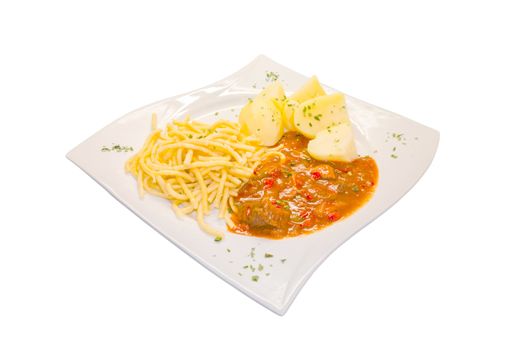 Beef stew on a plate with potatoes and pasta. Goulash is a stew which comes from Hungary.