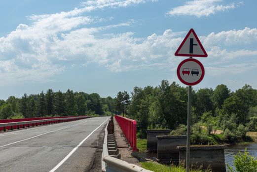 two signs on the road before the bridge