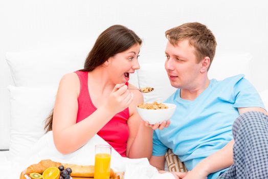 wife feeding her husband breakfast in bed