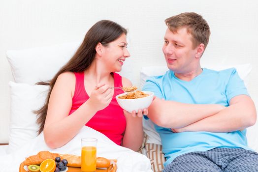 happy young couple having breakfast in bed together