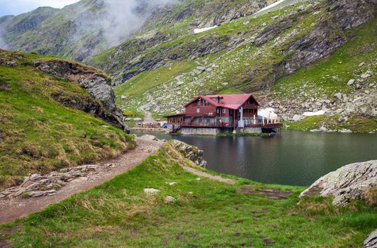 BALEA LAKE, ROMANIA - JUNE 24, 2012: Idyllic view with typical lodge on Balea Lake shore in Fagaras Mountains, Romania.