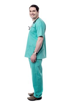 Side pose of smiling male doctor standing over white