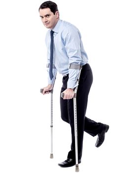 Businessman trying to walk with crutches over white