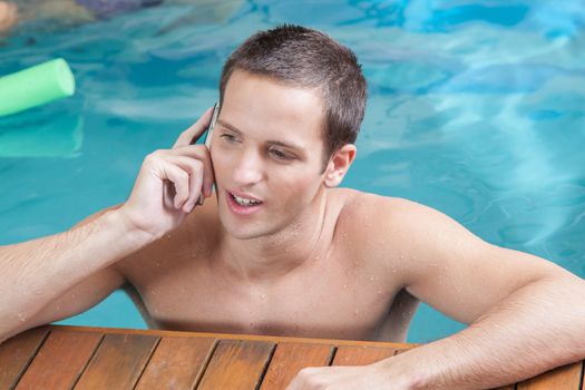 Man talking on telephone in the edge of the pool