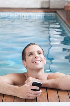 Man holding a cellphone in the edge of the pool