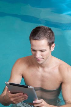 Man play with a tablet inside the pool