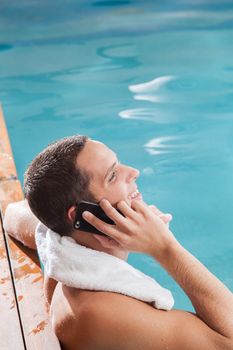 Man use the cellphone in the edge of the pool
