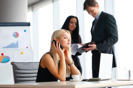 Young cute businesswoman talking on phone in office