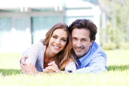 happy couple lying in front of their house