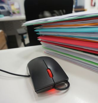Computer mouse and document folder placed on desk at office.                              