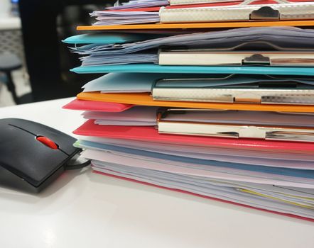 Stack of many color clipboard with document and computer mouse on desk at office.                               
