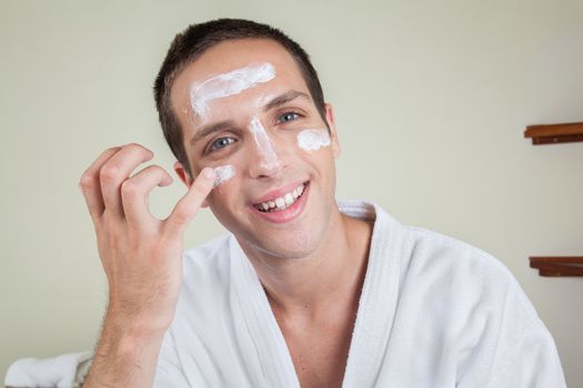 Happy man putting on face cream