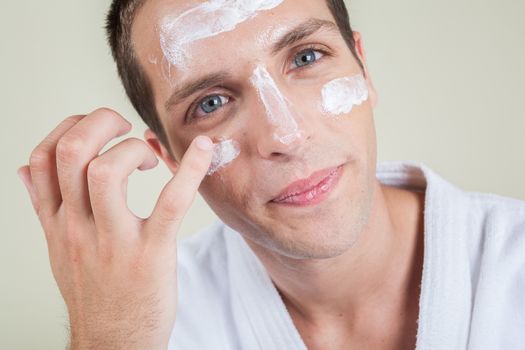 Serious man putting face cream with your finger
