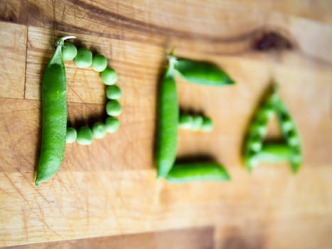 Word PEA created with peas on a wooden board with shallow depth of field