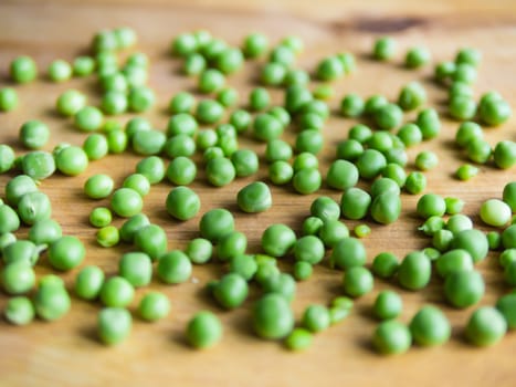 Scattered podded peas on a wooden board, soft focus