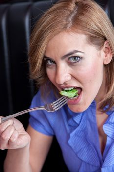 Woman is eating broccoli