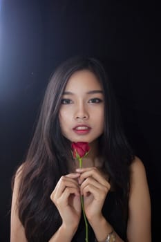 Beautiful asian women and red rose on black background .