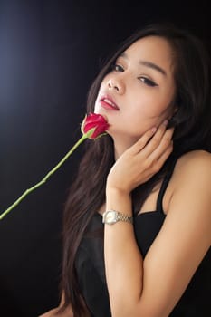 Beautiful asian women and red rose on black background .