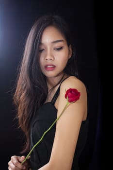 Beautiful asian women and red rose on black background .