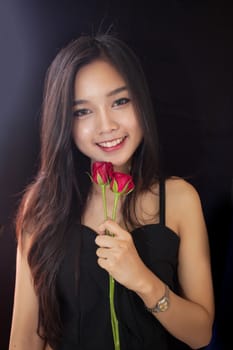 Beautiful asian women and red rose on black background .