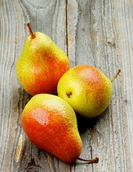 Three Ripe Yellow and Red Pears isolated on Rustic Wooden background