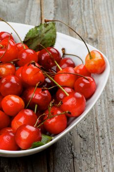 Heap of Fresh Ripe Sweet Maraschino Cherries in White Bowl Cross Section on Rustic Wooden background
