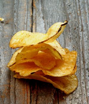 Arrangement of Crunchy Potato Chips closeup on Rustic Wooden background