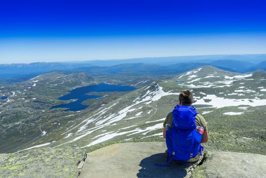 Hiker with big traveling rucksack looking forward on the mountain trail, adventure travel and discovery