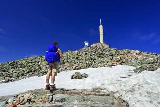 Hiker with big traveling rucksack looking forward on the mountain trail, adventure travel and discovery