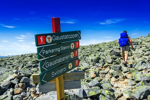 Hiker with big traveling rucksack looking forward on the mountain trail, adventure travel and discovery