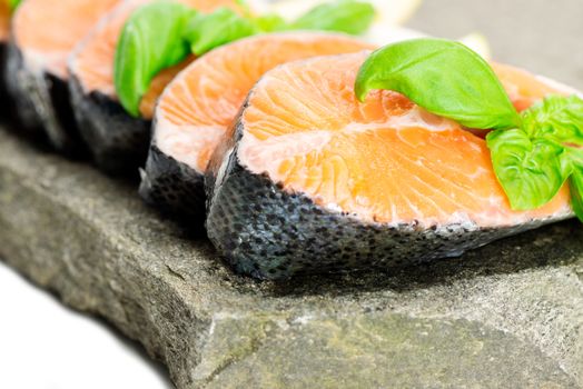 Salmon cuts on stone with basil and lemon