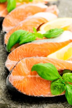 Salmon cuts on stone with basil and lemon