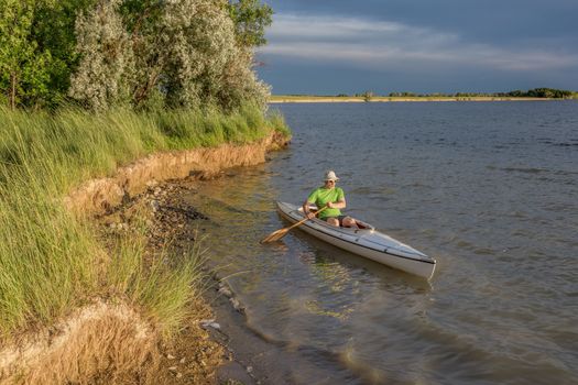 male paddler paddling a decked expedition canoe on a lake in northern Colorado