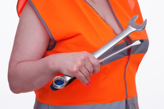 Woman in orange vest holds a wrench and screw-driver in hand