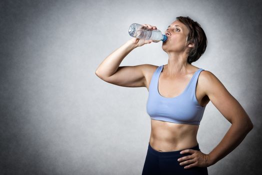 Image of middle aged handsome woman drinking water from a bottle