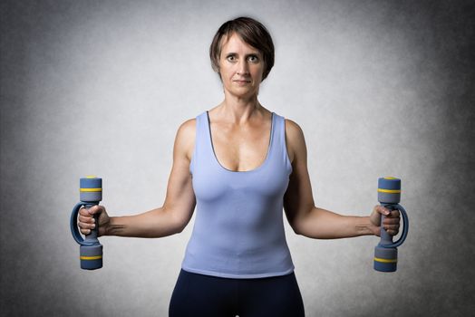 Middle aged handsome woman exercising with dumbbells