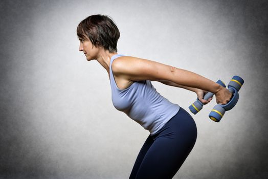 Middle aged handsome woman exercising with dumbbells