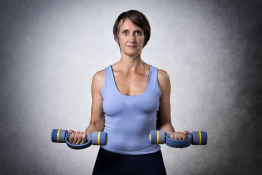 Middle aged handsome woman exercising with dumbbells