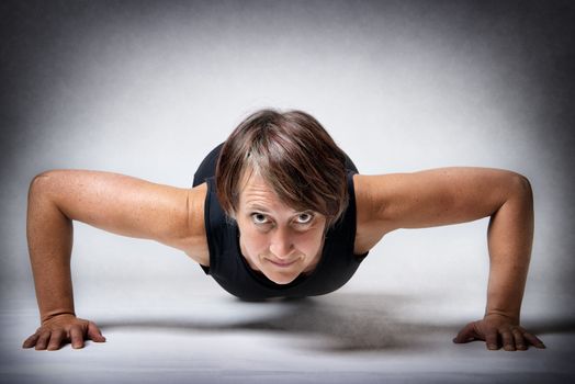 Middle aged handsome woman doing push-ups