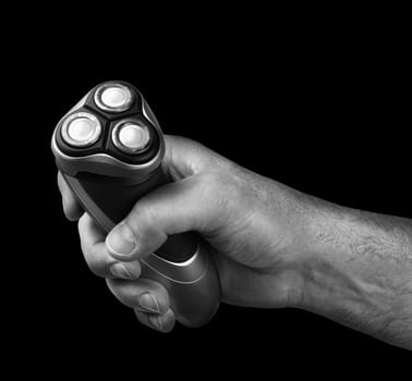 Strong male hand holding electric razor shaver black background