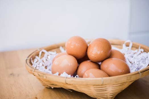 Brown eggs in a wicker basket on a wooden table