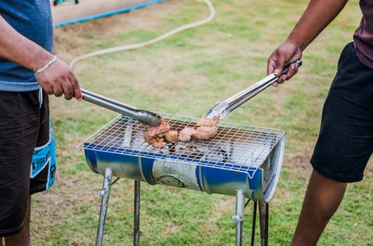 Man hands grilling meat on a grill outdoors
