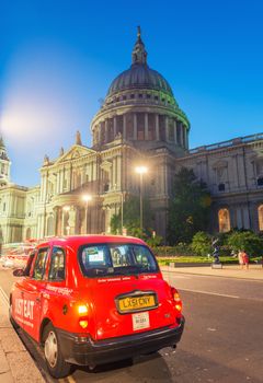 LONDON - JUNE 12, 2015: Red cab under Saint Paul Cathedral at night. There are more than 20,000 taxis in London.
