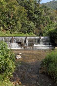 Small weir in valley with water flowing over