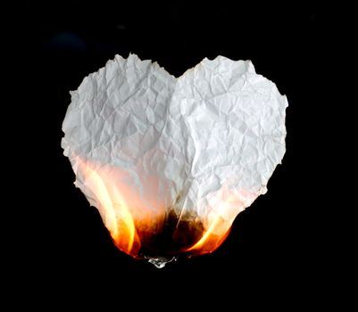 crumpled heart shape paper burning on black background